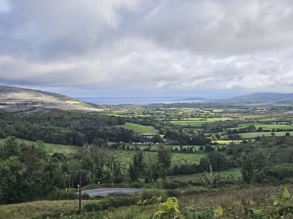 Green fields and limestone hills of the Burren in County Clare stretching out towards Galway Bay