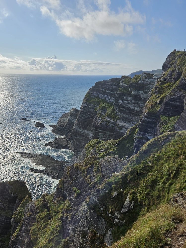 Layered sea cliffs dropping into a sunlit Atlantic on the Kerry coast