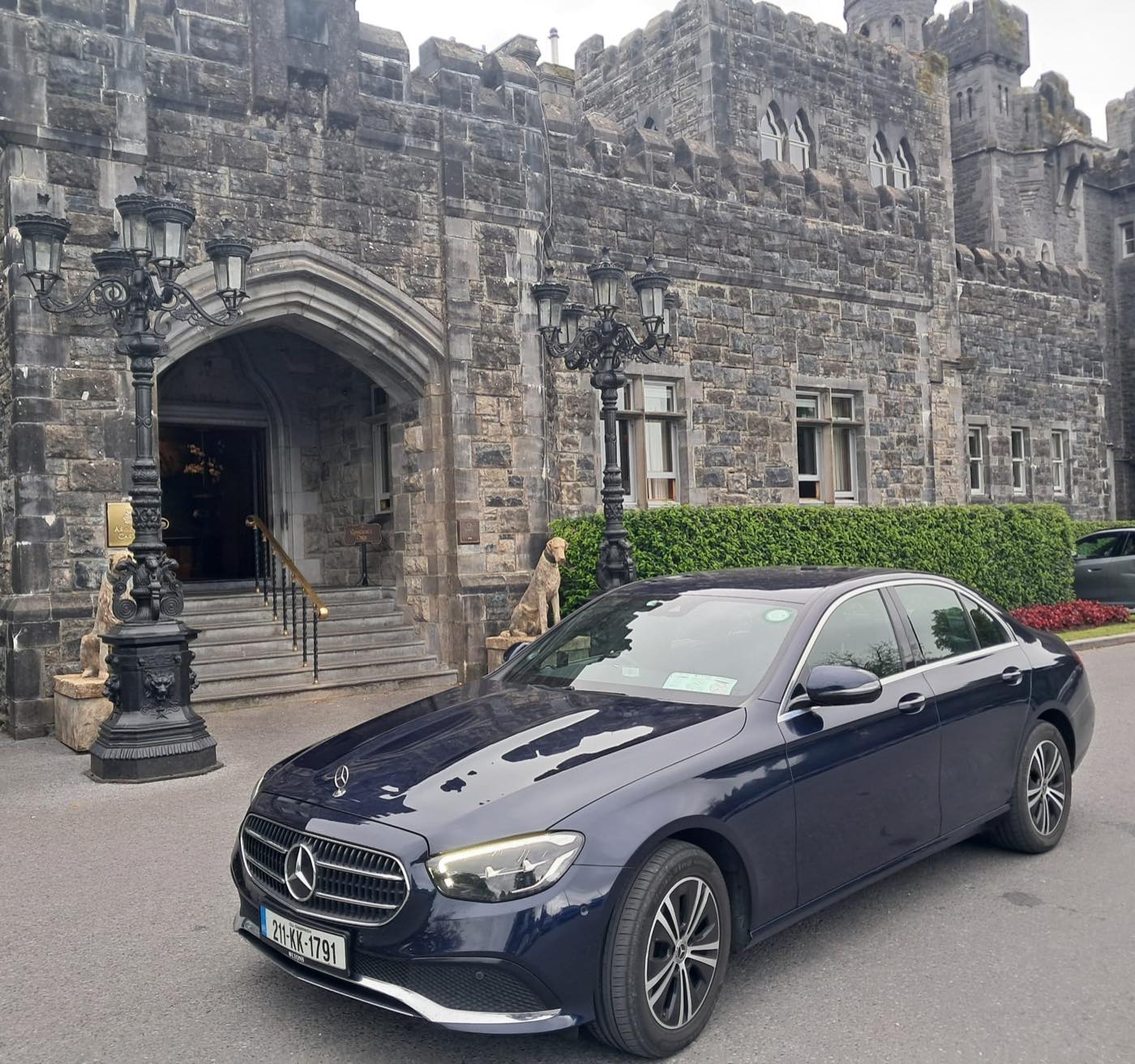Navy Mercedes-Benz E-Class arriving at a grand castle hotel entrance for a wedding